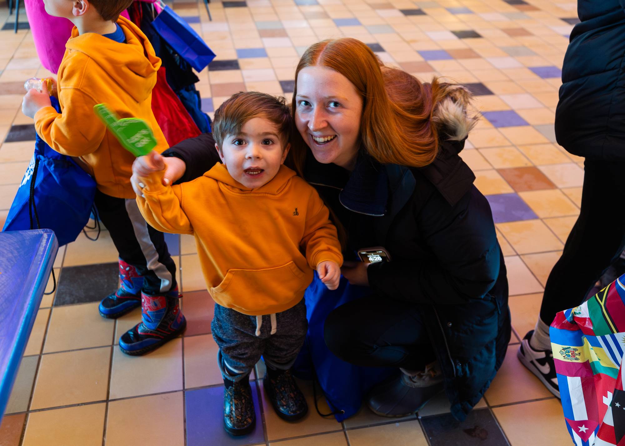 A student and a child holding a small green foam finger smile for the camera